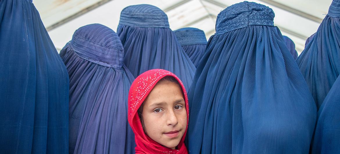 Afghan girls stand among women in blue burqas amid ongoing restrictions that bar girls from secondary education in Afghanistan.